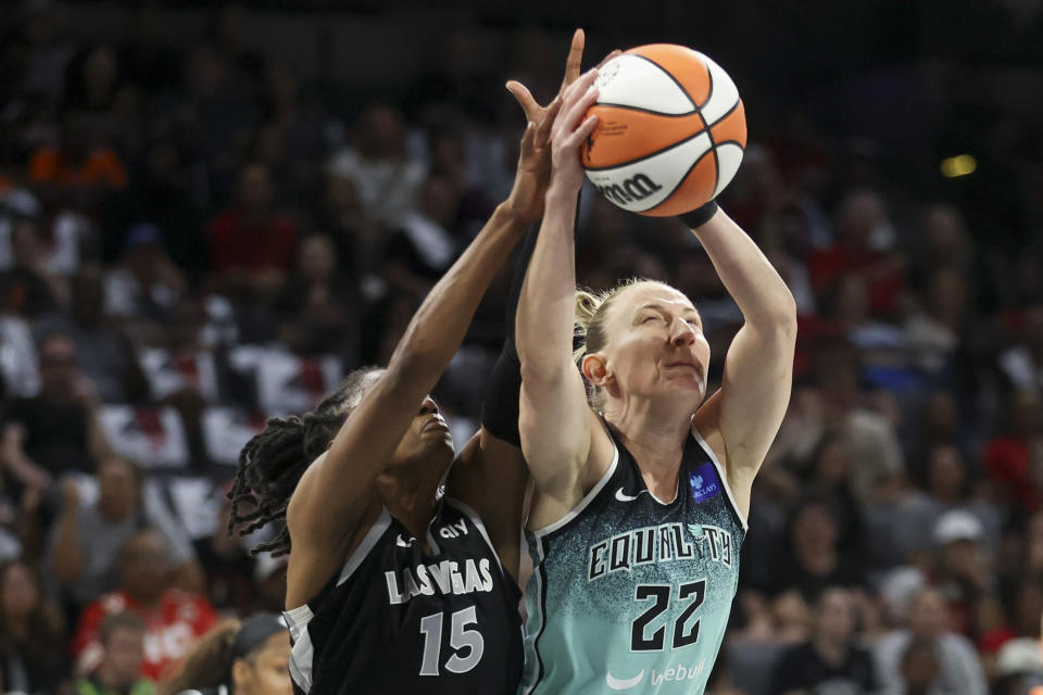 New York Liberty guard Courtney Vandersloot (22) grabs a rebound over Las Vegas Aces guard Tiffany Hayes (15) during the first half of a WNBA Semifinal basketball game, Sunday, Oct. 6, 2024, in Las Vegas. (AP Photo/Ian Maule)