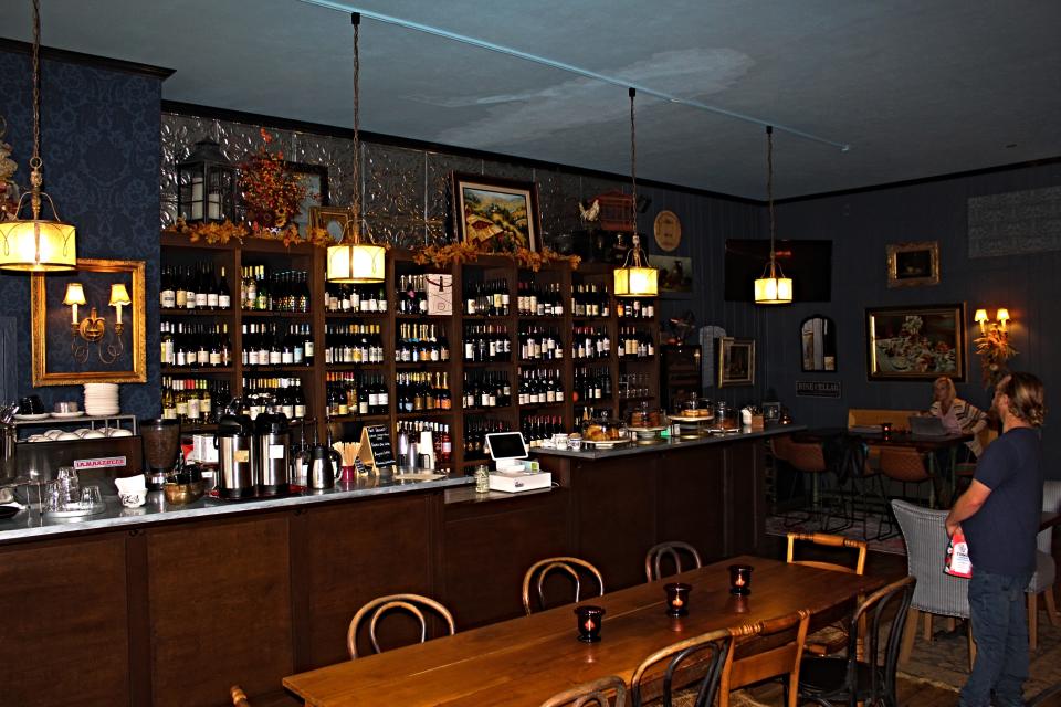 The interior of Réveille coffee and The Wine Cellar Bistro features walls lined with bottles of wine from different regions of the world and a variety of Tinker Coffee Roastery beans and blends.