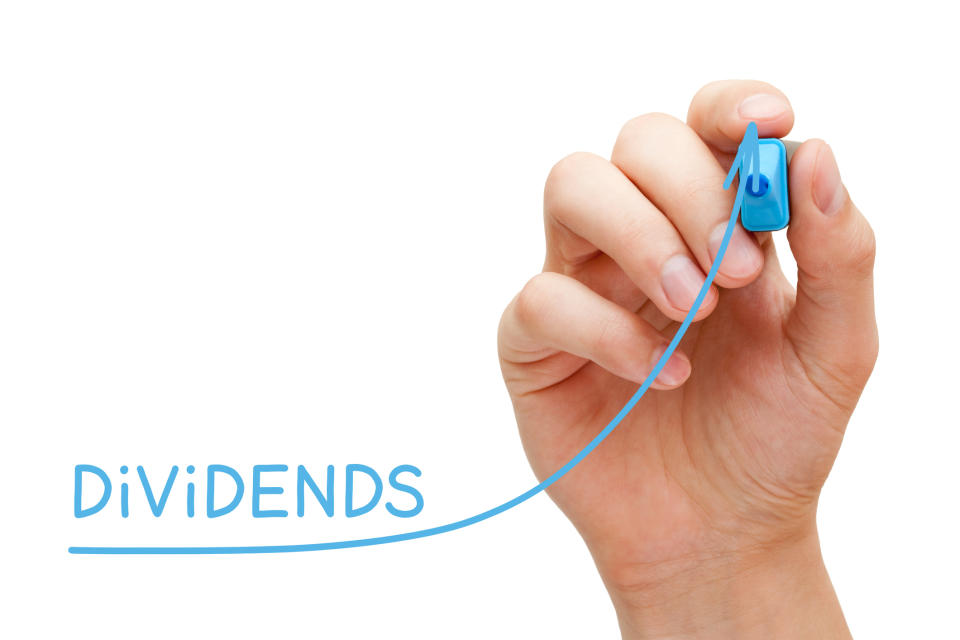 A hand draws an upward sloping blue line next to the word dividends written  in blue.