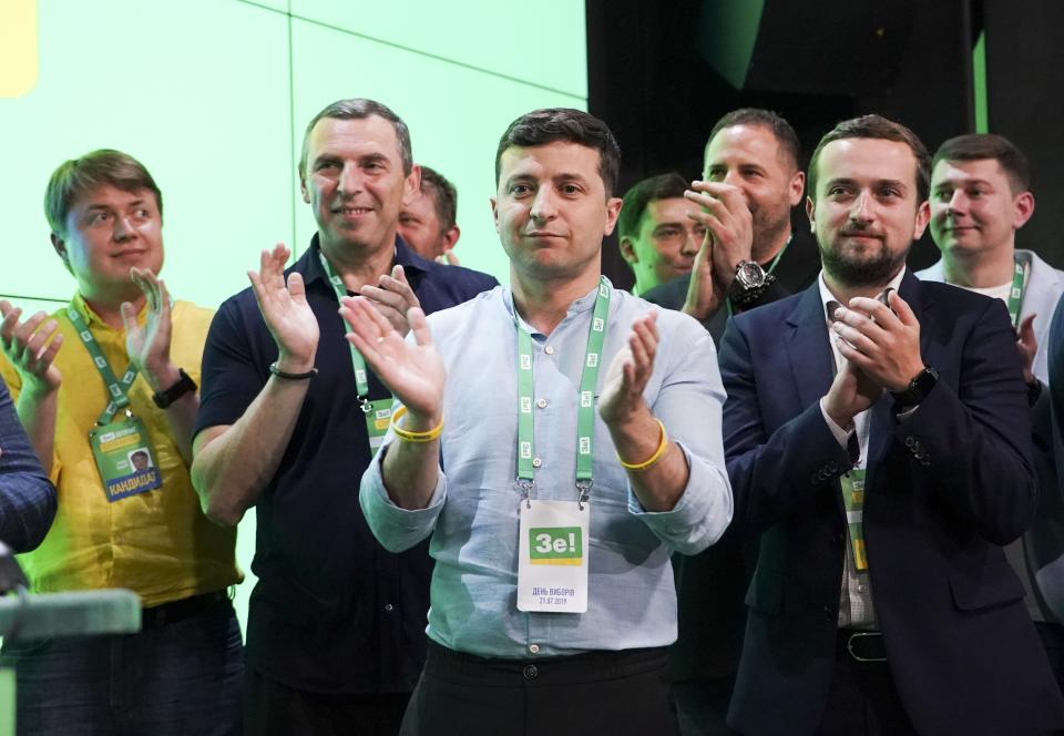 Ukrainian President Volodymyr Zelenskiy, center, applauds with his team at his party's headquarters after a parliamentary election in Kiev, Ukraine, Sunday, July 21, 2019. Zelenskiy's party took the largest share of votes in the country's snap parliamentary election, an exit poll showed Sunday. (AP Photo/Evgeniy Maloletka)