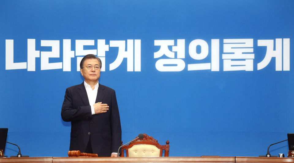 South Korean President Moon Jae-in salutes to a national flag during an emergency cabinet meeting at the presidential Blue House in Seoul, South Korea, Friday, Aug. 2, 2019. Moon has vowed stern countermeasures against Japan's decision to downgrade its trade status, which he described as a deliberate attempt to contain South Korea's economic growth and a "selfish" act that would damage global supply chains. The signs read: "Righteous." (Bae Jae-man/Yonhap via AP)