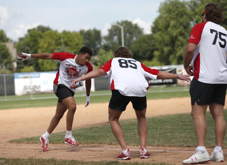 Chimere Dike, left, celebrates hitting a home run with Clay Cundiff (85) and Joe Tippmann (75) during the Braelon Allen Charity Softball Game July 17, 2022, in Fond du Lac, Wis.