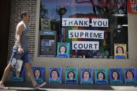 A man walks past a store front displaying paintings of Caitlyn Jenner and a sign thanking the U.S. Supreme Court in West Hollywood, California, United States, June 26, 2015. REUTERS/Lucy Nicholson