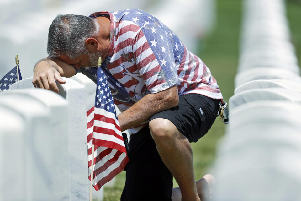 J.D. Madrid pauses for a moment at the grave of his father-in-law, Michael McBrien, in Fort Logan National Cemetery, Saturday, May 23, 2020, in Sheridan, Colo. Both Madrid and his father-in-law served in the U.S. Navy. While traditional events such as placing flags at the foot of gravestones for service members and ceremonies to mark Memorial Day were cancelled because of coronavirus concerns, survivors came out in force to offer their own tributes. (AP Photo/David Zalubowski)