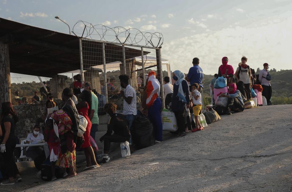 Migrants wait in queue to enter a temporary camp near Mytilene town, on the northeastern island of Lesbos, Greece, Saturday, Sept. 12, 2020. Greek authorities have been scrambling to find a way to house more than 12,000 people left in need of emergency shelter on the island after the fires deliberately set on Tuesday and Wednesday night gutted the Moria refugee camp. (AP Photo/Petros Giannakouris)