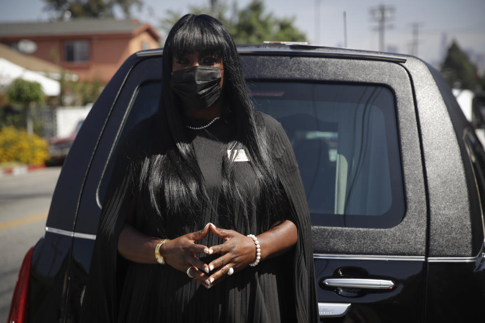 Candy Boyd, owner of Boyd Funeral Home, poses for a photo in front of a hearse before a funeral service for Lydia Nunez, who died from COVID-19, at the Metropolitan Baptist Church Tuesday, July 21, 2020, in Los Angeles. When people began dying from the coronavirus in the United States, for a few weeks funeral home owner Boyd declined to receive the remains of such patients. (AP Photo/Marcio Jose Sanchez)