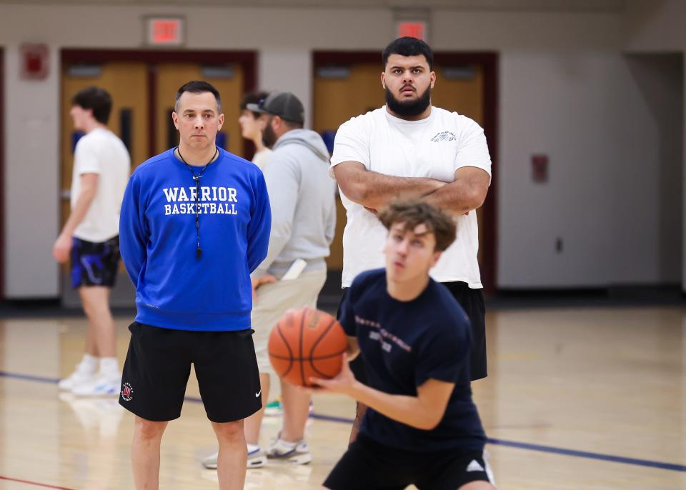 Winnacunnet High School boys basketball head coach Jay McKenna, left, and assistant coach Seth Provencher watch as senior Tyson Khalil handles the ball during a 3-on-3 drill at Tuesday's practice.