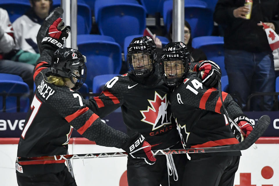 Canada forward Blayre Turnbull, center, celebrates with forward Laura Stacey, left, and defenseman Renata Fast after scoring against Czechia during the first period of a semifinal at the women's world hockey championships in Utica, N.Y., Saturday, April 13, 2024. (AP Photo/Adrian Kraus)