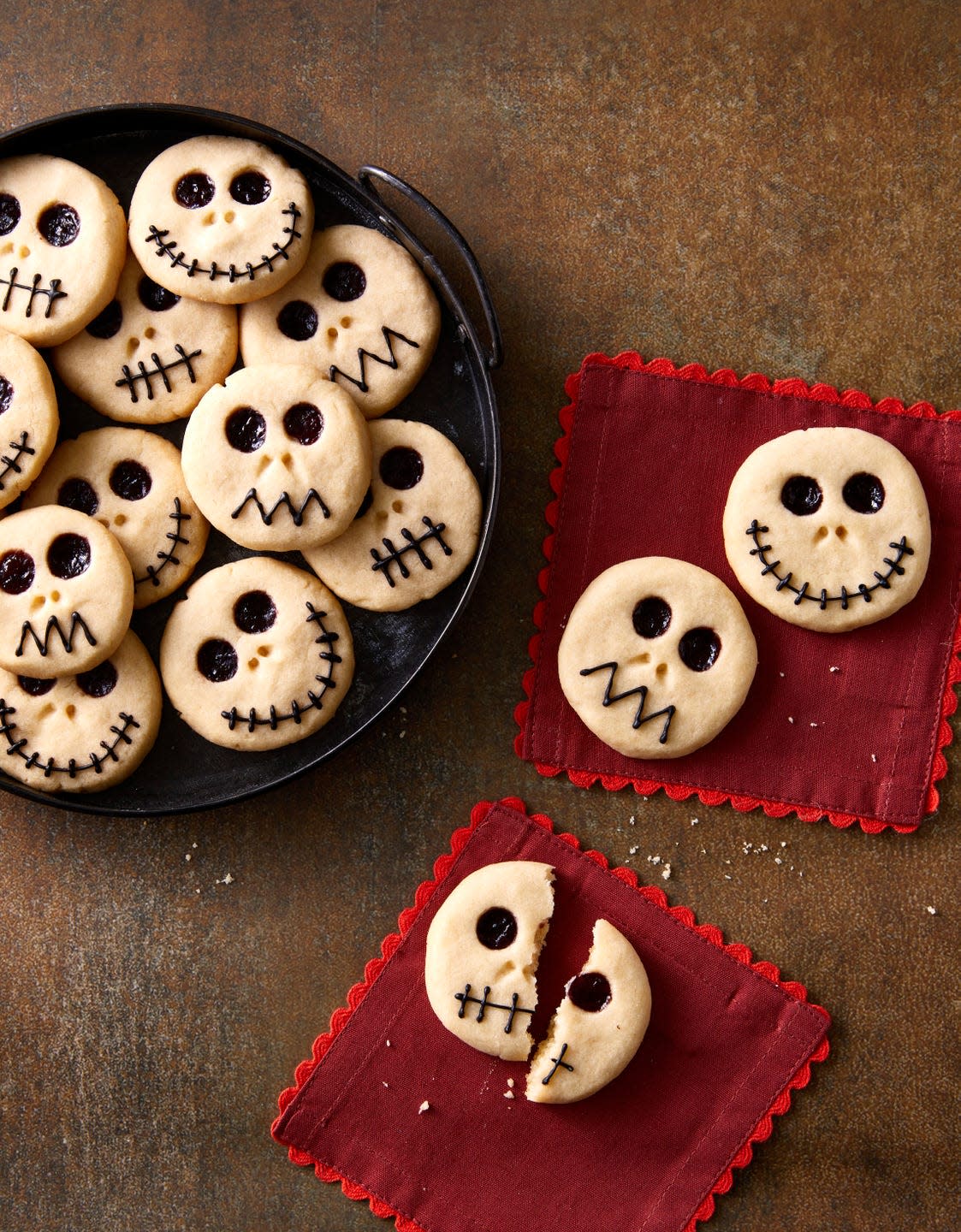 skeleton thumbprint cookies on a black plate and on red napkins