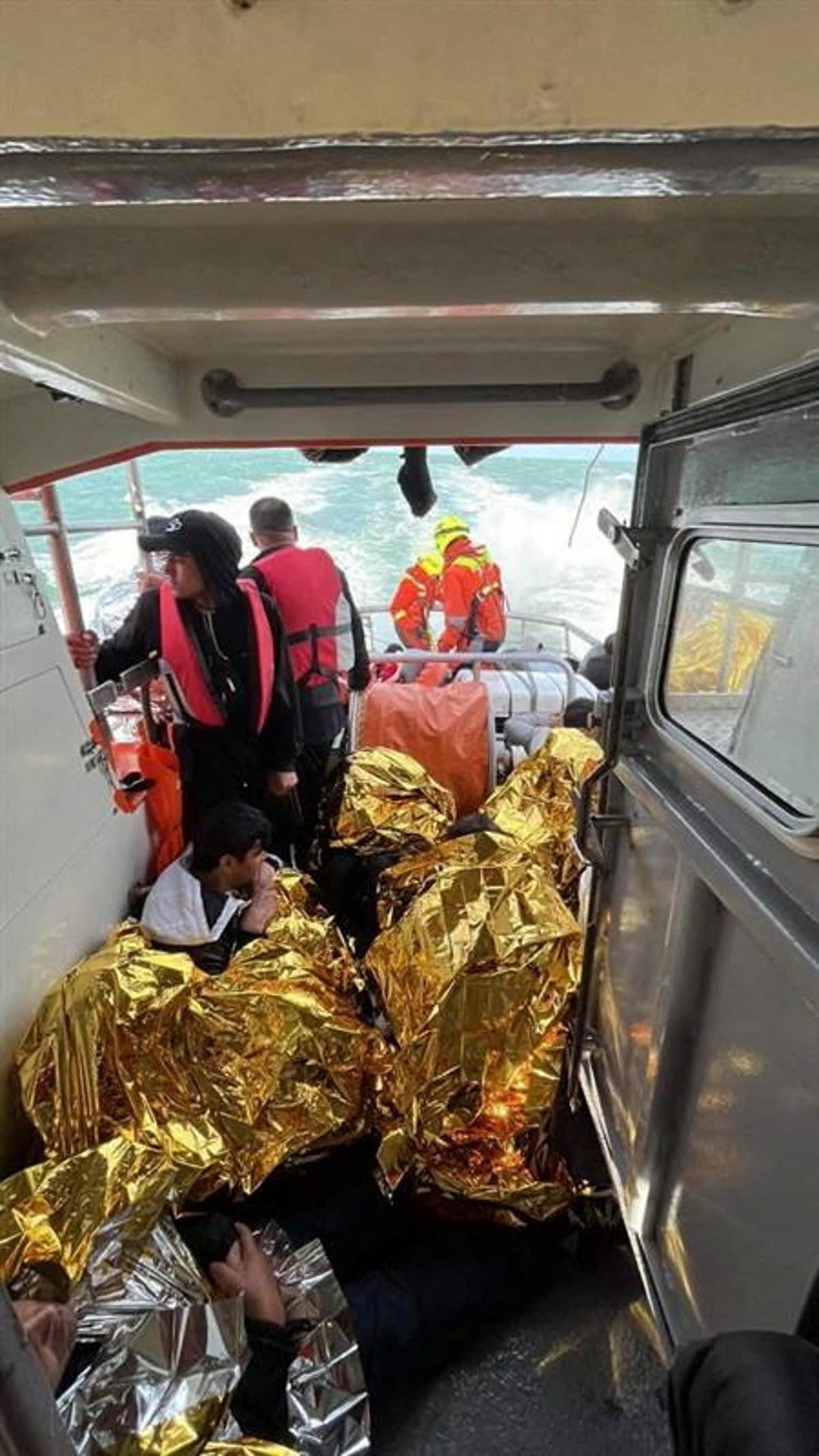 Rescued migrants sit on the ‘Notre Dame du Risban’ after a migrant boat trying to cross the Channel from France capsized (Reuters)