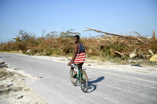 A boy bikes past destroyed trees in The Mudd neighbourhood of Marsh Harbour