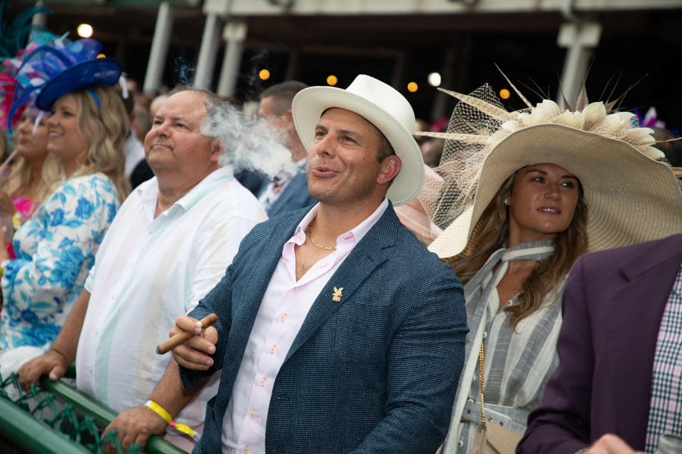 A man smokes a cigar at Churchill Downs.