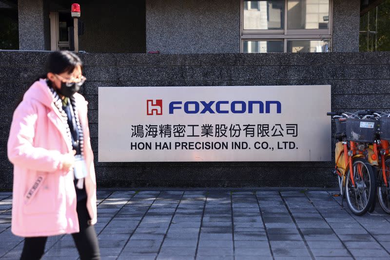 FILE PHOTO: A woman walks past the logo of Foxconn outside a company's building, in New Taipe City