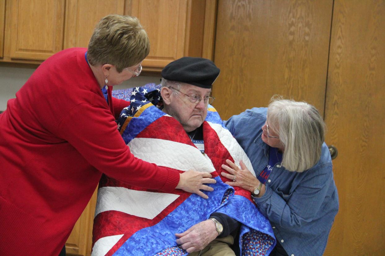 Members of the Perry Piecemakers help wrap James Michael Kelley in a Quilt of Valor during a presentation on on Friday, Nov. 10, 2023, at the Perry Elks Lodge.