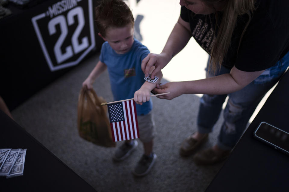 A child gets sticker from Mission 22, a nonprofit that is focused on ending military and veteran suicide, Saturday, June 10, 2023, at a festival in Jacksonville, Texas. (AP Photo/David Goldman)