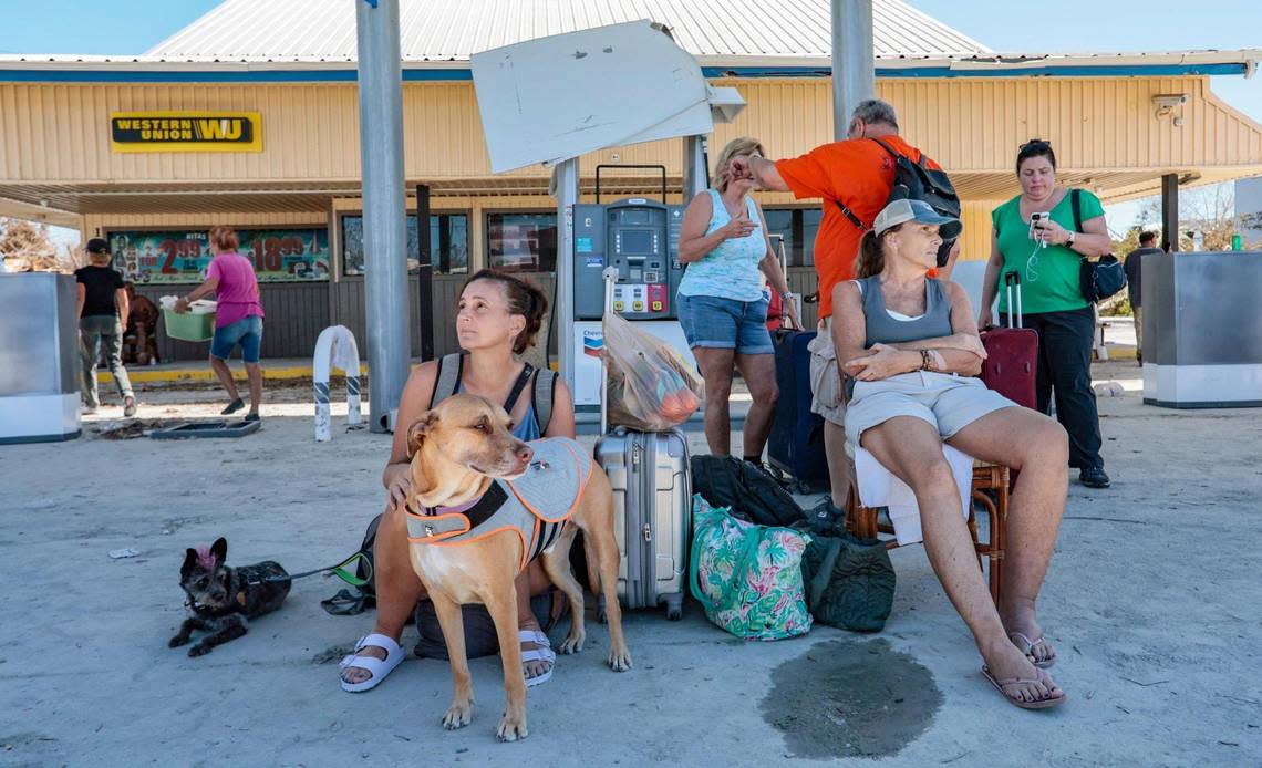 Hurricane Ian evacuees Brandy Batz, 45, her mom Cathy Batz, 66, and their dogs Buns and Kip of Fort Myers Beach arrive on San Marco Island as they wait for transportation on Monday.