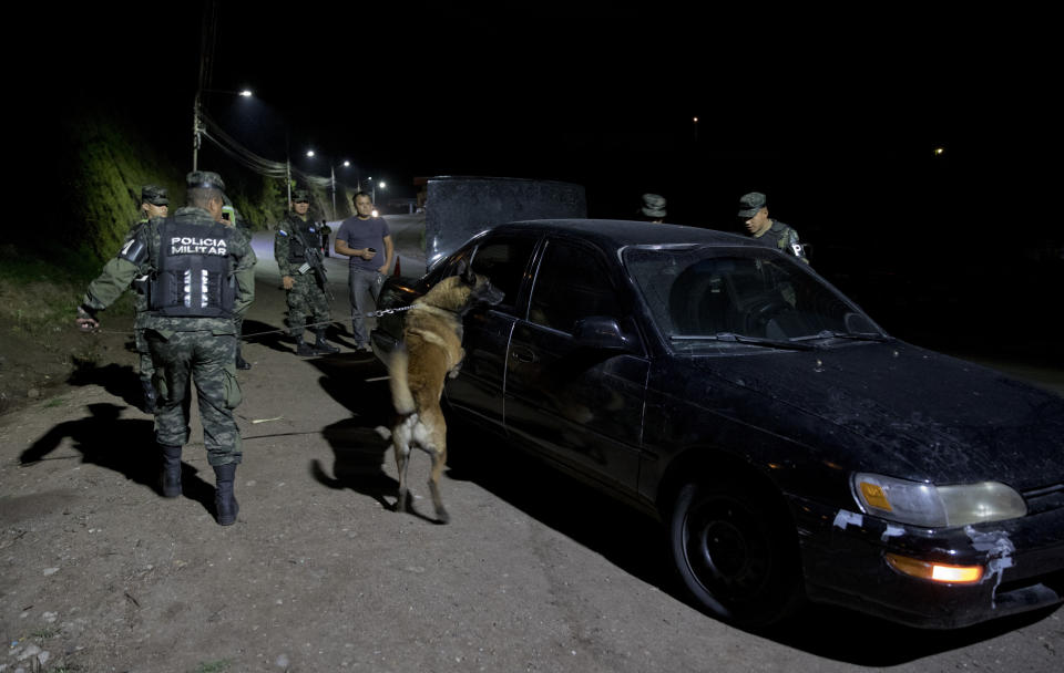 Soldiers with a search dog check a car as they patrol Tegucigalpa, Honduras, Wednesday, Aug. 21, 2019. President Juan Orlando Hernández pointed to the two dozen drug traffickers extradited to the U.S. under his administration as proof that he was not working with them. (AP Photo/Eduardo Verdugo)