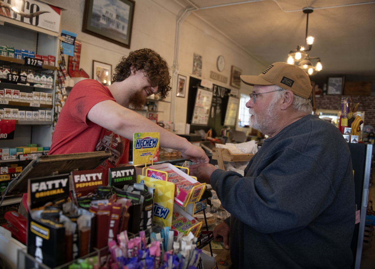Ben Scandlon, 20, employee and son of Chatham General Store owner Beverly Scandlon, hands change to John Fleming, a Chatham resident purchasing items including a Kmart sub on Thursday, April 18.