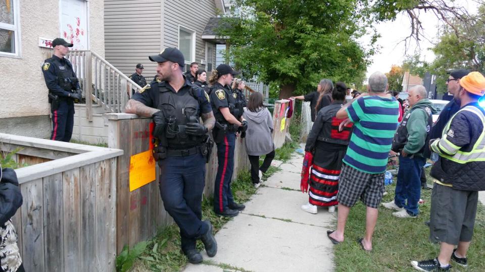 Police officers stand between a group of protesters and Kyle Klochko's house on Wednesday evening. (Walther Bernal/CBC - image credit)