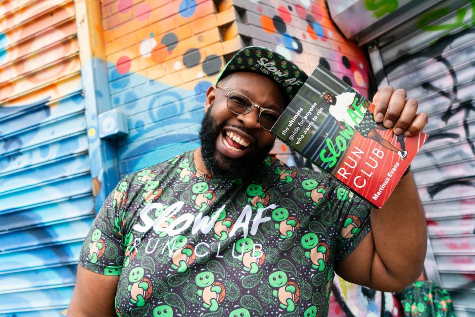 Martinus Evans, Detroit native and founder of Slow AF, poses with the recent publication “Slow AF Run Club: The Ultimate Guide for Anyone that Wants to Run”