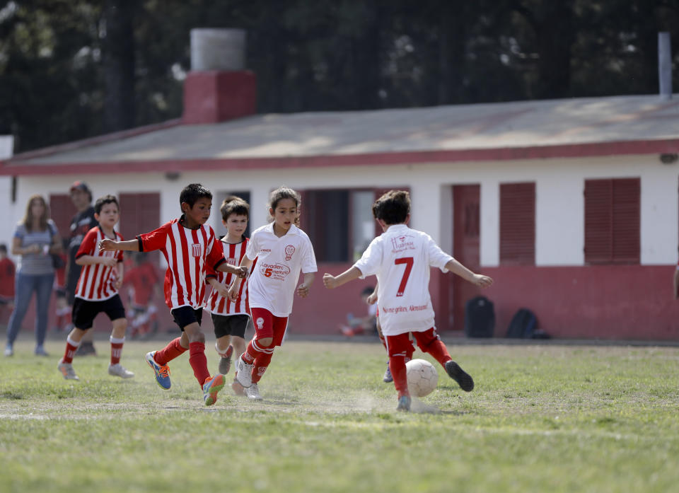 In this Sept. 8, 2018 photo Candelaria Cabrera, center, plays with her soccer teammates against the Alumni Club, in Chabas, Argentina. While she's officially now banned from playing with Huracan because she is a girl, the team has let her keep playing, at least until an opponent objects. (AP Photo/Natacha Pisarenko)