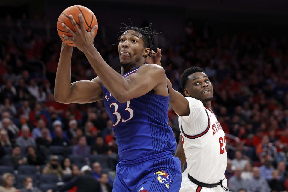 Kansas forward David McCormack (33) drives to the basket past St. John's guard Montez Mathis during the first half of an NCAA college basketball game Friday, Dec. 3, 2021, in Elmont, N.Y. (AP Photo/Adam Hunger)