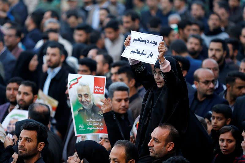A girl holds a sign during a funeral procession for Soleimani and al-Muhandis, in Ahvaz