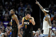Phoenix Suns guard Devin Booker (1) rubs his forehead after a three pointer by Minnesota Timberwolves guard Nickeil Alexander-Walker, right, during the second half of Game 3 of an NBA basketball first-round playoff series, Friday, April 26, 2024, in Phoenix. (AP Photo/Matt York)
