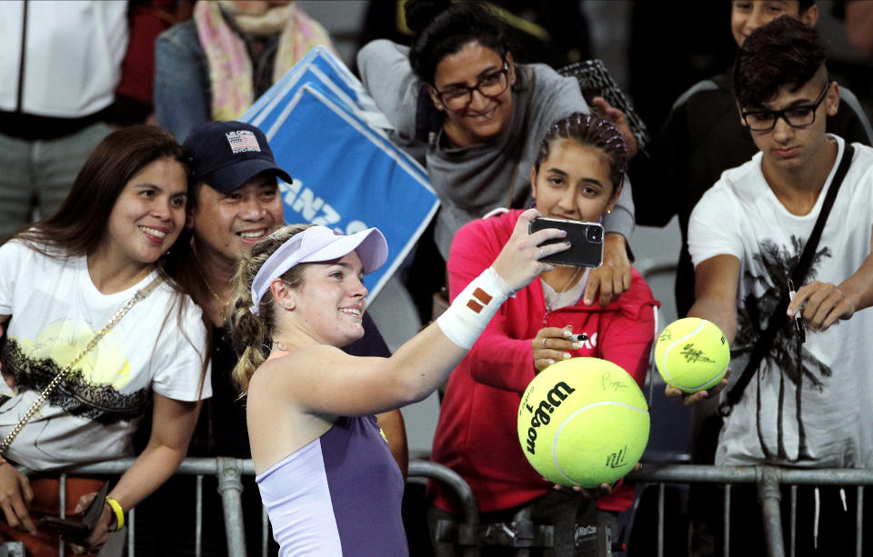 Catherine McNally of the United States takes a selfie with spectators after defeating Australia's Samantha Stosur in their first round singles match at the Australian Open tennis championship in Melbourne, Australia, Monday, Jan. 20, 2020. (AP Photo/Andy Wong)