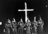 <p>A group of Ku Klux Klansman, wearing their robes, stand in front of a burning cross at Stone Mountain, Georgia in 1971. (Photo: Getty Images) </p>