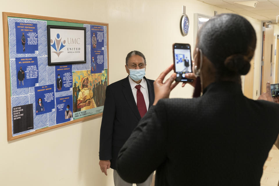 In this Wednesday, Feb. 10, 2021, photo Wallace Charles Smith, 72, who is a pastor at Shiloh Baptist Church, has his picture taken, by United Medical Center's Vice President of Public Relations Toya Carmichael, at the hospital in southeast Washington. The hospital has a board of quotes and photographs from people who have been vaccinated against COVID-19 to encourage others to receive the vaccine. (AP Photo/Jacquelyn Martin)