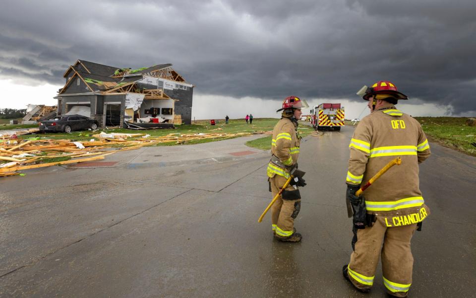Firefighters assess the damage to houses after a tornado passed through the area near Omaha