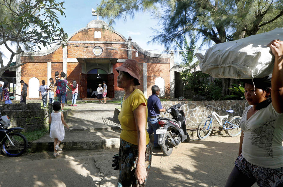 In this Jan. 27, 2019 photo, pedestrians walk past the chapel built by U.S. priest Father Pius Hendricks in the village of Talustusan on Biliran Island in the central Philippines. Since December 2018, the small village has been rocked by controversy after about 20 boys and men accused the Catholic parish priest of years of alleged sexual abuse. (AP Photo/Bullit Marquez)