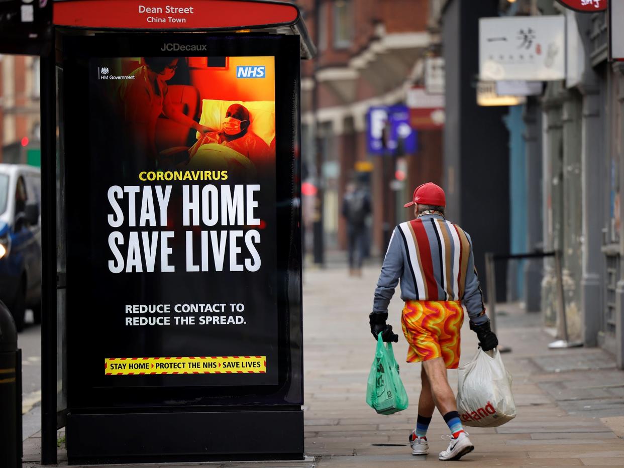A shopper walks past NHS signage promoting ’Stay Home, Save Lives’ on a bus shelter in central London in January 2021 (AFP)