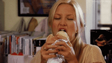 Kate Hudson eating a sandwich at her desk.