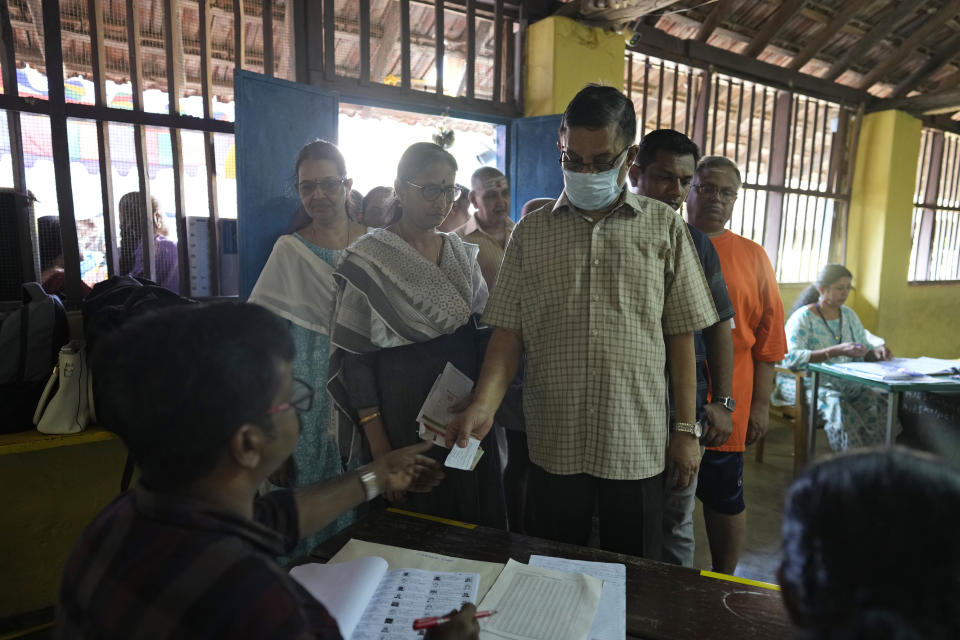 A man shows his identity papers to a polling official as people queue up to vote during the second round of voting in the six-week-long national election near Palakkad, in Indian southern state of Kerala, Friday, April 26, 2024. (AP Photo/Manish Swarup)
