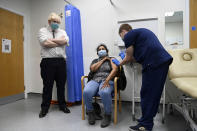 FILE - British Prime Minister Boris Johnson, left, watches as a patient receives a COVID-19 vaccine during his visit to the Lordship Lane Primary care center where he met staff and people receiving their booster vaccines, in London, Tuesday, Nov. 30, 2021. The coronavirus's omicron variant kept a jittery world off-kilter Wednesday Dec. 1, 2021, as reports of infections linked to the mutant strain cropped up in more parts of the globe, and one official said that the wait for more information on its dangers felt like “an eternity.” (Paul Grover/Pool Photo via AP, File)