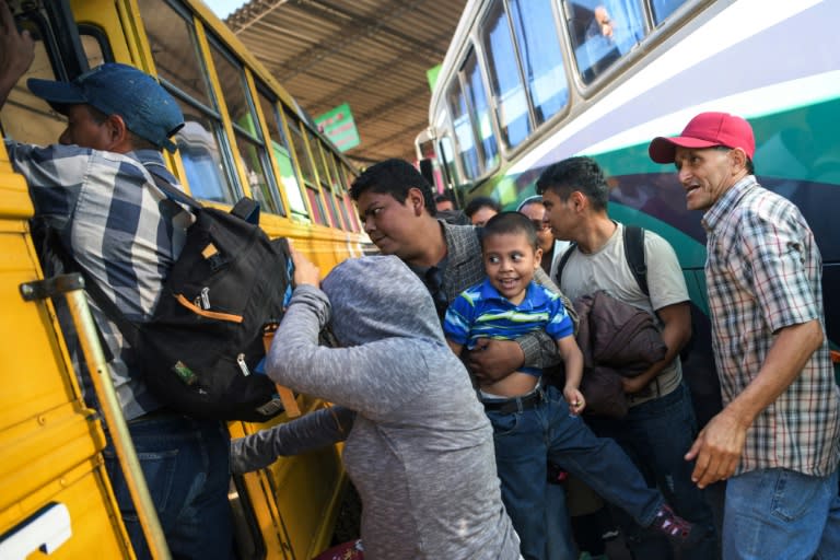 Salvadoran migrants board a bus, beginning their journeys in a caravan headed for the United States