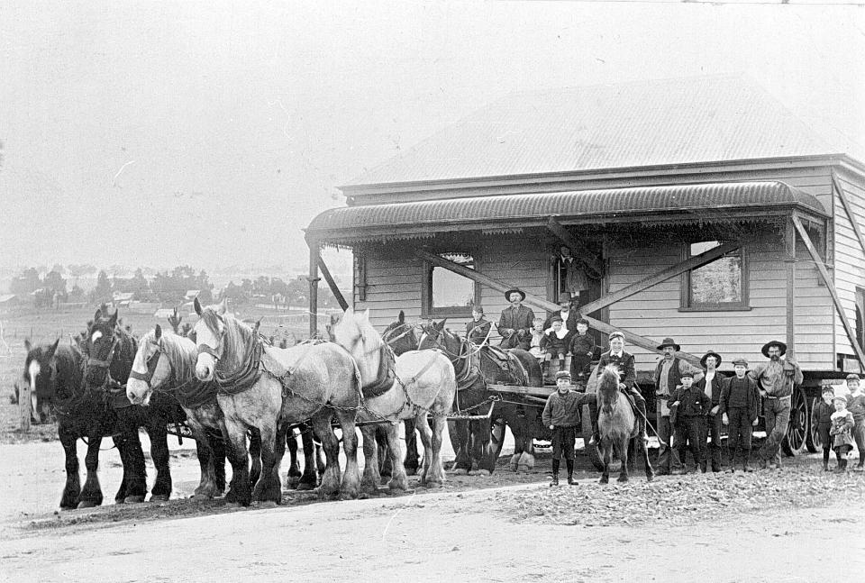 Columns of horses pulling a house, with lots of men on horseback