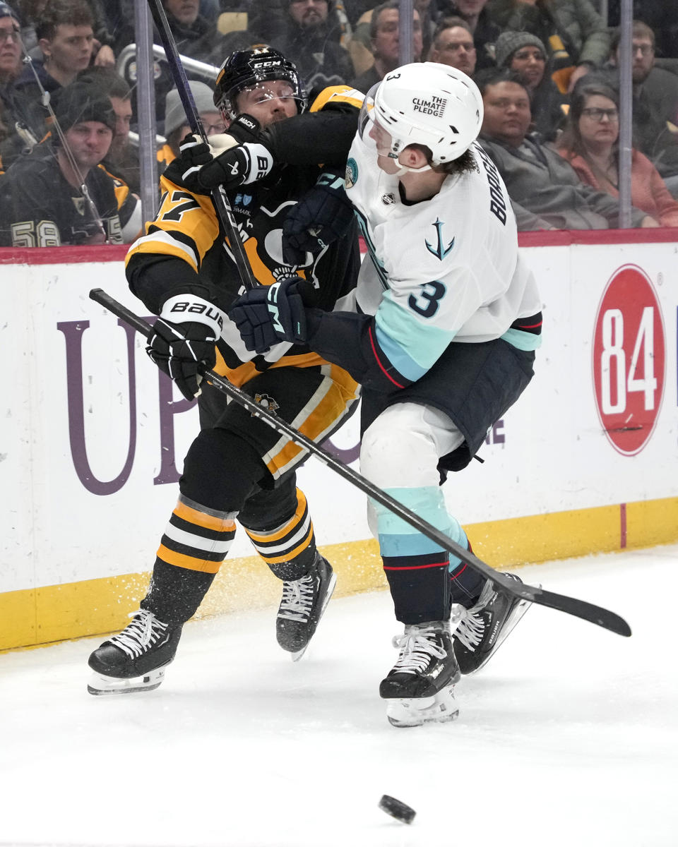 Pittsburgh Penguins' Bryan Rust, left, is checked off the puck by Seattle Kraken's Will Borgen (3) during the second period of an NHL hockey game in Pittsburgh, Monday, Jan. 15, 2024. (AP Photo/Gene J. Puskar)