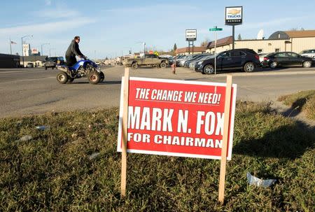 A man on an all-terrain vehicle passes a campaign signs for Three Affiliated Tribes council chairman candidate Mark Fox in New Town on the Fort Berthold Reservation in North Dakota, November 1, 2014. REUTERS/Andrew Cullen