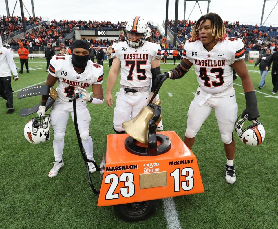 Massillon players Shon Robinson, left, Michael Looney,middle, and Malachi Card,right, ring the victory bell mid-field after defeting McKinley at Tom Benson Hall of Fame Stadium Saturday , October 21, 2023.