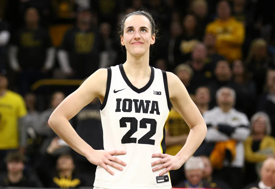 IOWA CITY, IOWA- FEBRUARY 15:  Guard Caitlin Clark #22 of the Iowa Hawkeyes listens as the crowd cheers after breaking the NCAA women's all-time scoring record during the game against the Michigan Wolverines  at Carver-Hawkeye Arena on February 15, 2024 in Iowa City, Iowa.  (Photo by Matthew Holst/Getty Images)