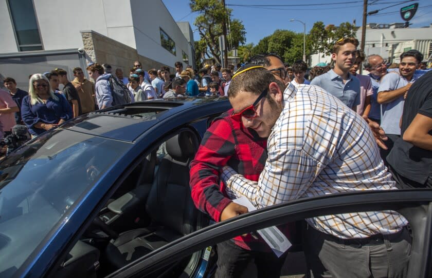 Los Angeles, CA - August 25: Student Shimmi Jotkowitz, 17, hugs his teacher Julio Castro, outside YULA Boys High School on Thursday, Aug. 25, 2022, in Los Angeles, CA. Students at YULA Boys High School, a private Jewish school on the Westside, have raised $30,000 to buy a MAZDA 3 GT for their beloved teacher who currently commutes to work by bus and scooter. (Francine Orr / Los Angeles Times)