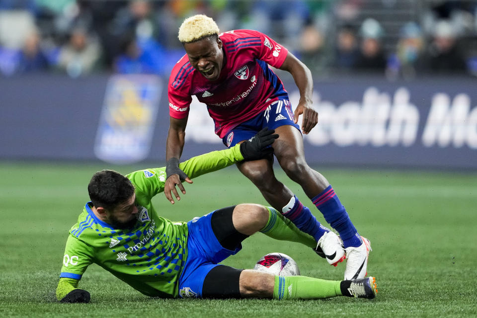 FC Dallas forward Bernard Kamungo (77) reacts while being tackled by Seattle Sounders midfielder João Paulo, left, during the first half of Game 3 of a first-round playoff MLS soccer match Friday, Nov. 10, 2023, in Seattle. (AP Photo/Lindsey Wasson)