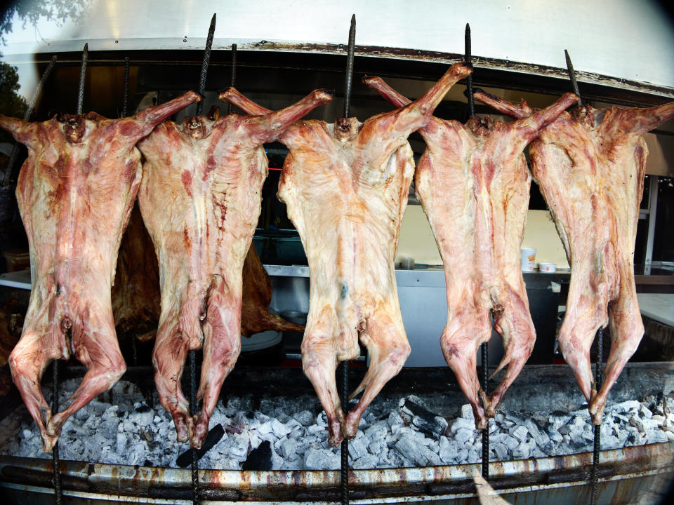 Roast goat meat hangs above hot coals in Monterrey, Mexico. (Photo: tirc83 via Getty Images)