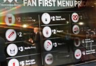 FILE - In this May 16, 2016, file photo, Atlanta Falcons president and CEO Rich McKay is reflected in a screen displaying the proposed concession stand menu prices inside Mercedes-Benz Stadium, home of the Falcons in Atlanta. The crippling grip the coronavirus pandemic has had on the sports world has forced universities, leagues and franchises to evaluate how they might someday welcome back fans. which thousands could be in close proximity. They gather in concourses to chat, buy food and drinks and await the start. They stand in lines at restrooms at halftime or between innings. Then they surge toward the exits at the final whistle or last out. (AP Photo/David Goldman, File)