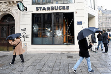 Graffiti is seen on a vandalized Starbucks coffee shop with broken store front windows the day after clashes during a national day of protest by the "yellow vests" movement and a climate change march in Paris, France, December 9, 2018. REUTERS/Piroschka van de Wouw