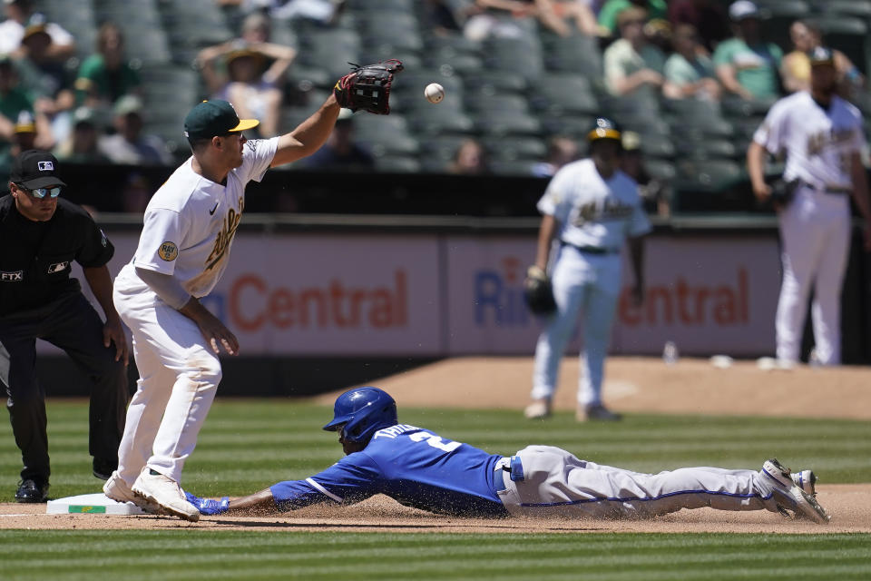 Kansas City Royals' Michael A. Taylor, bottom, slides into third base after hitting a triple next to Oakland Athletics third baseman Jonah Bride during the seventh inning of a baseball game in Oakland, Calif., Saturday, June 18, 2022. (AP Photo/Jeff Chiu)