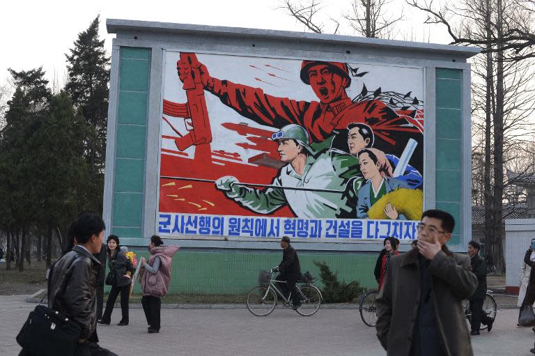 North Koreans stand in front of a political mural in Pyongyang on April 12, 2012